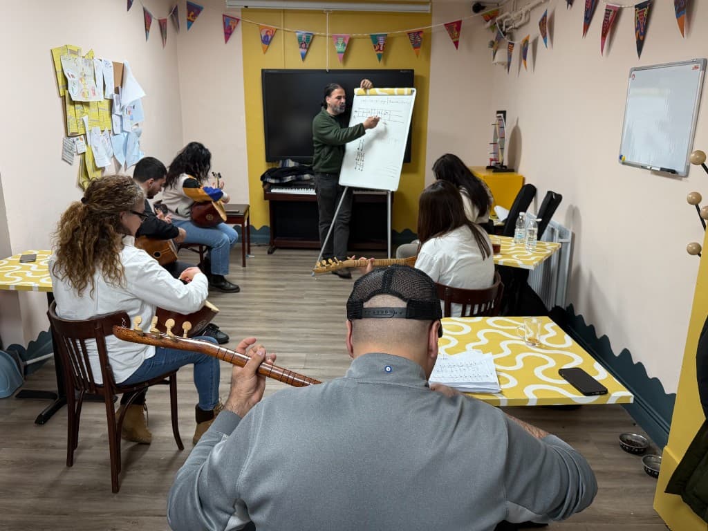 Unity of Migrant Workers’ta topluluk müzik sınıfında bağlama öğrenen yetişkinler
