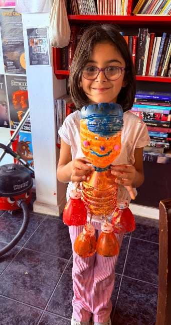 Bitmiş heykelini gururla sunan bir çocuk